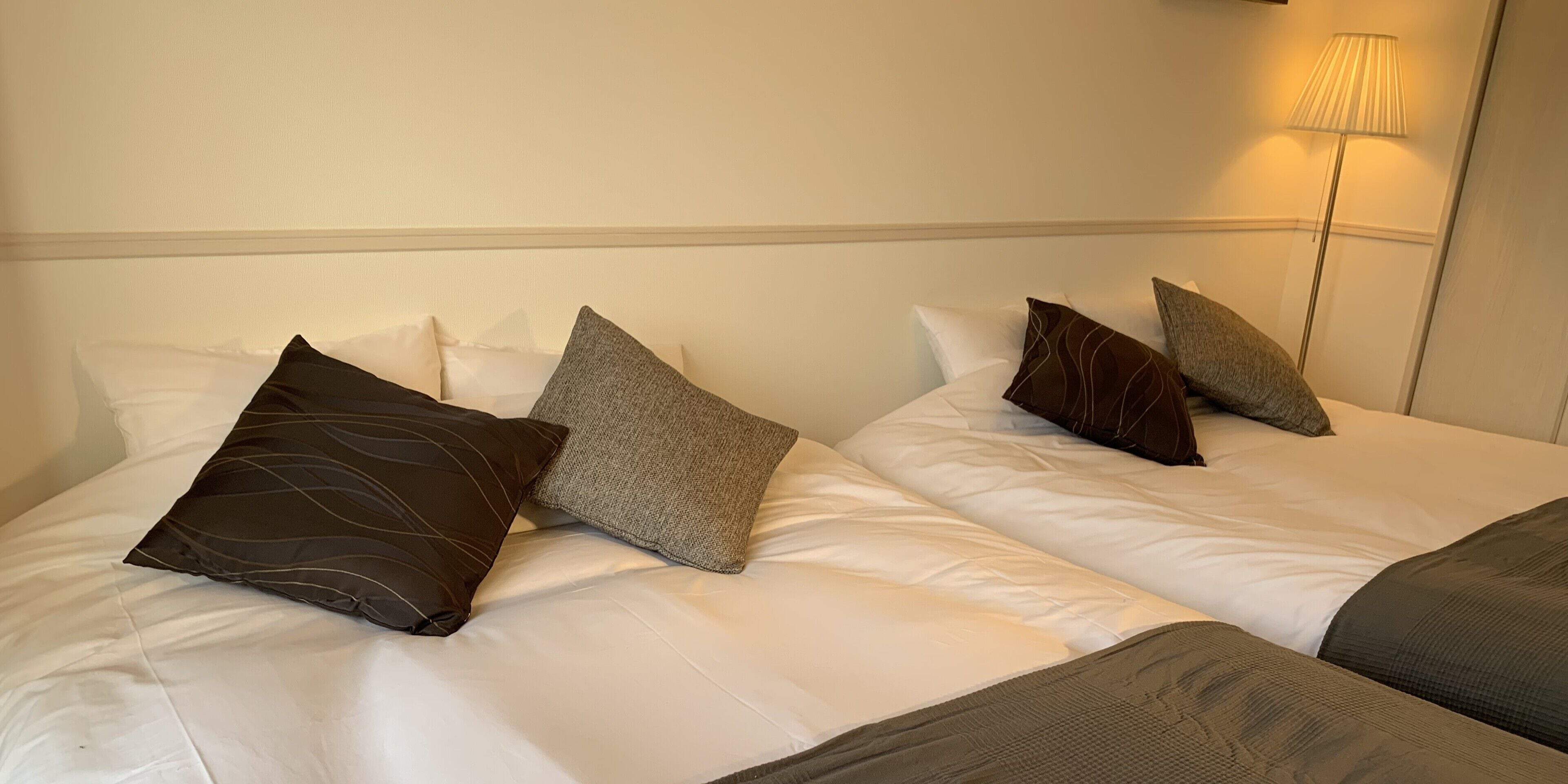A hotel room with two beds, each with white bedding and multiple pillows.