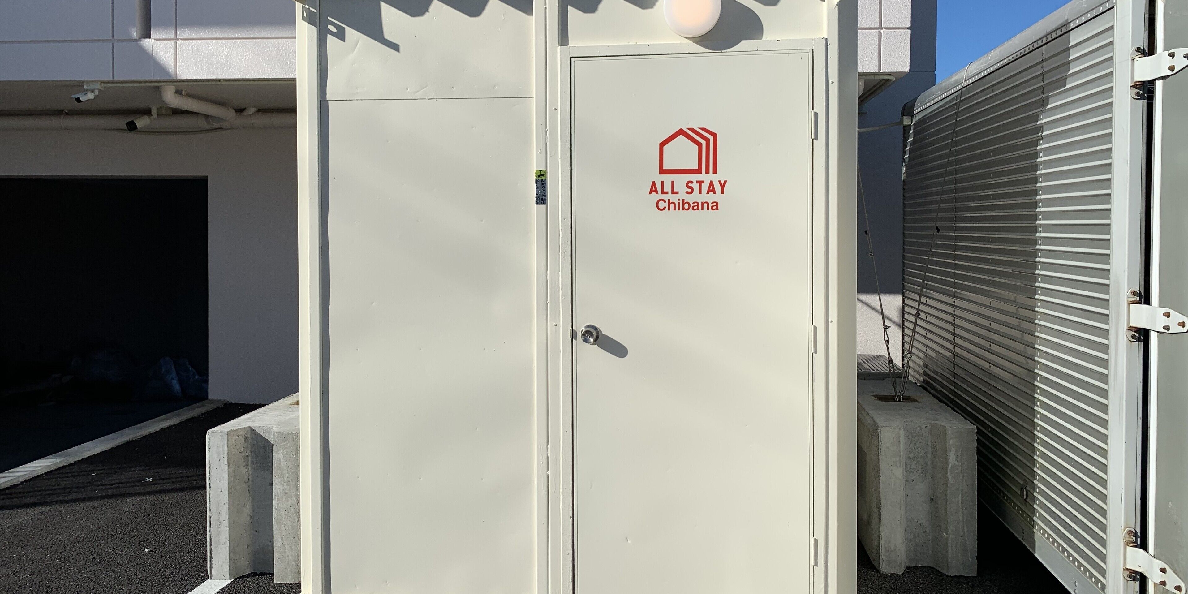 Una puerta metálica blanca, con un logotipo y la inscripción 'ALL STAY Chibana'.