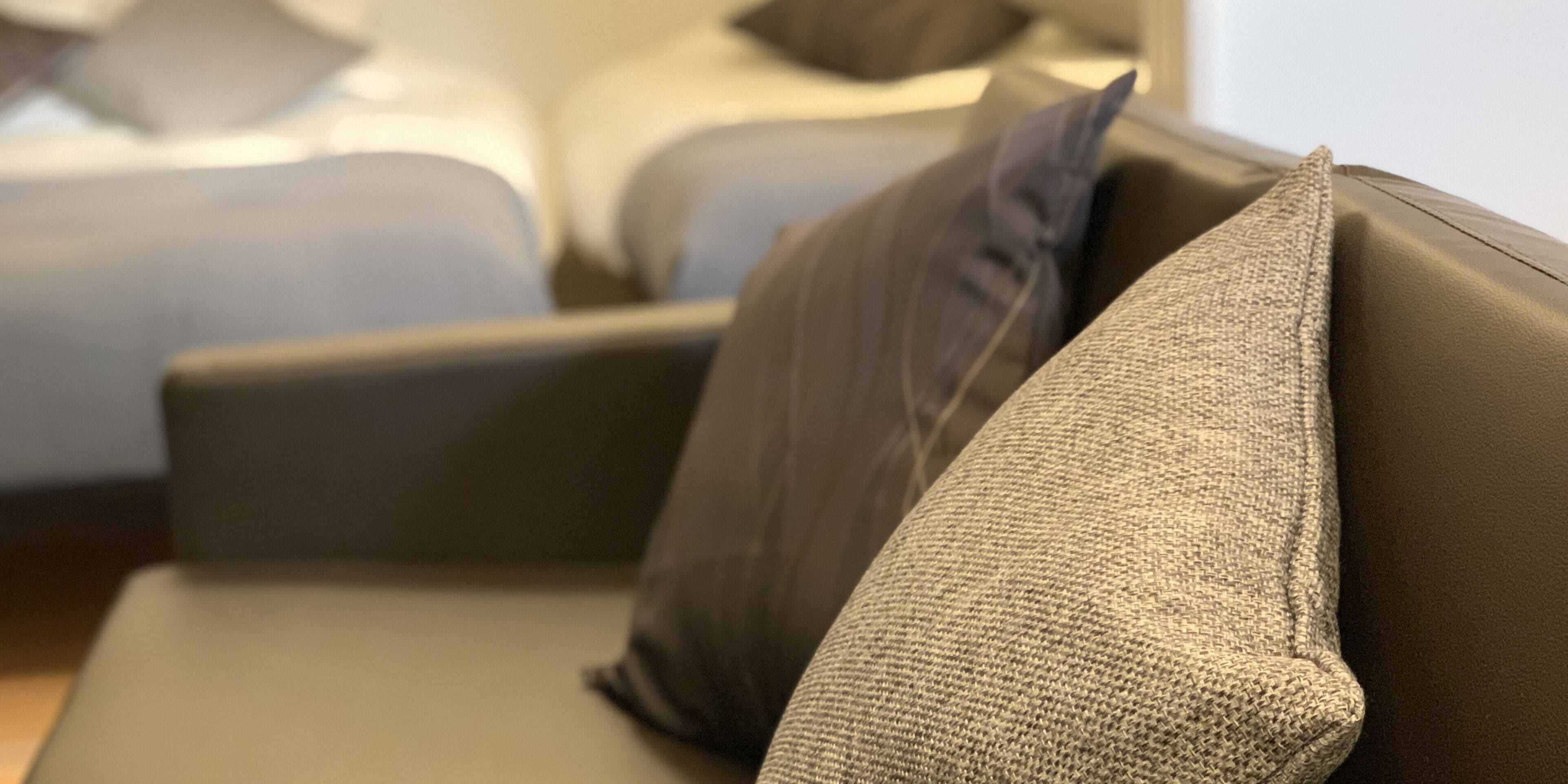 A close-up of a sofa with a textured cushion and a dark pillow.