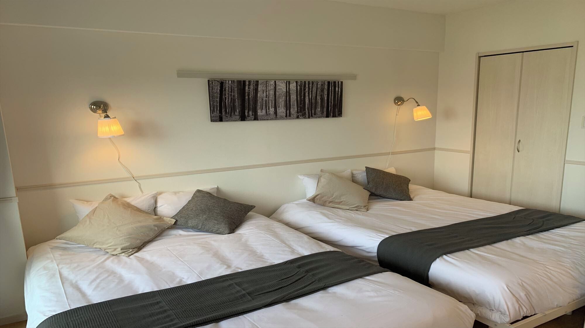 Ein Hotelzimmer mit zwei Betten, einem Schrank und einem Bild an der Wand.