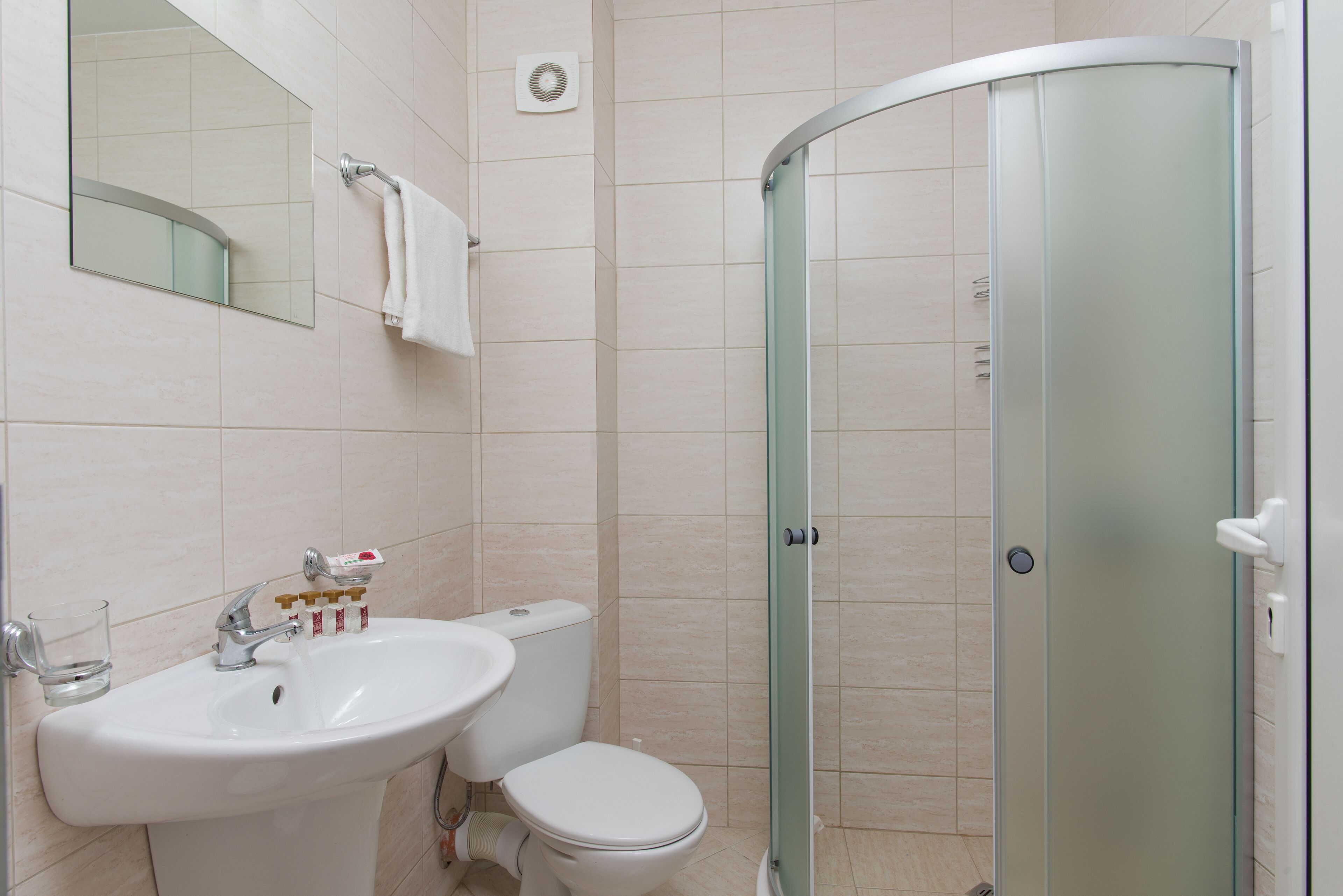 A bathroom with a sink, toilet, and a glass-enclosed shower.