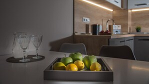 Una cocina moderna con una bandeja de fruta en la mesa, un fregadero y armarios.