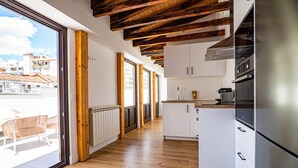 Une cuisine moderne avec des poutres en bois, des armoires blanches et une grande fenêtre donnant sur un paysage urbain.