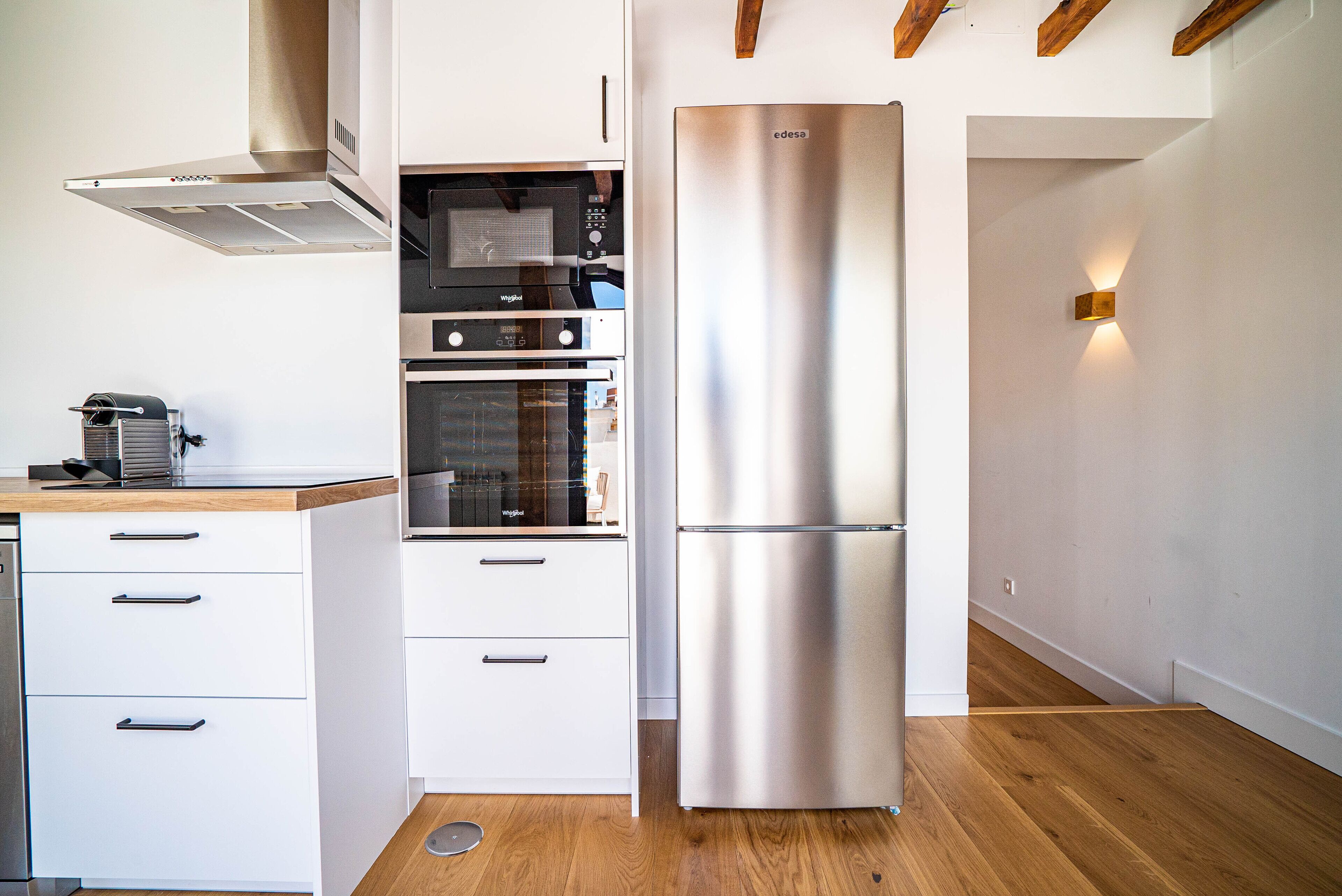 Een moderne keuken met roestvrijstalen apparatuur, houten vloeren en witte keukenkastjes.