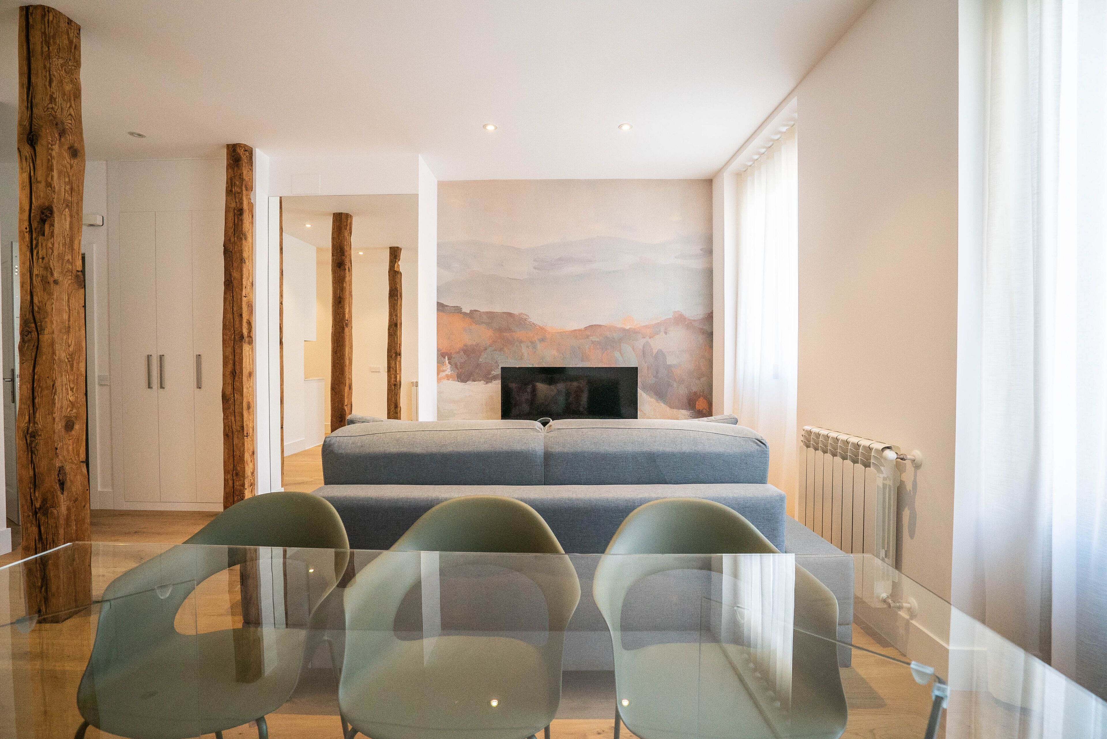 A modern living room with a sofa, glass dining table, and chairs.