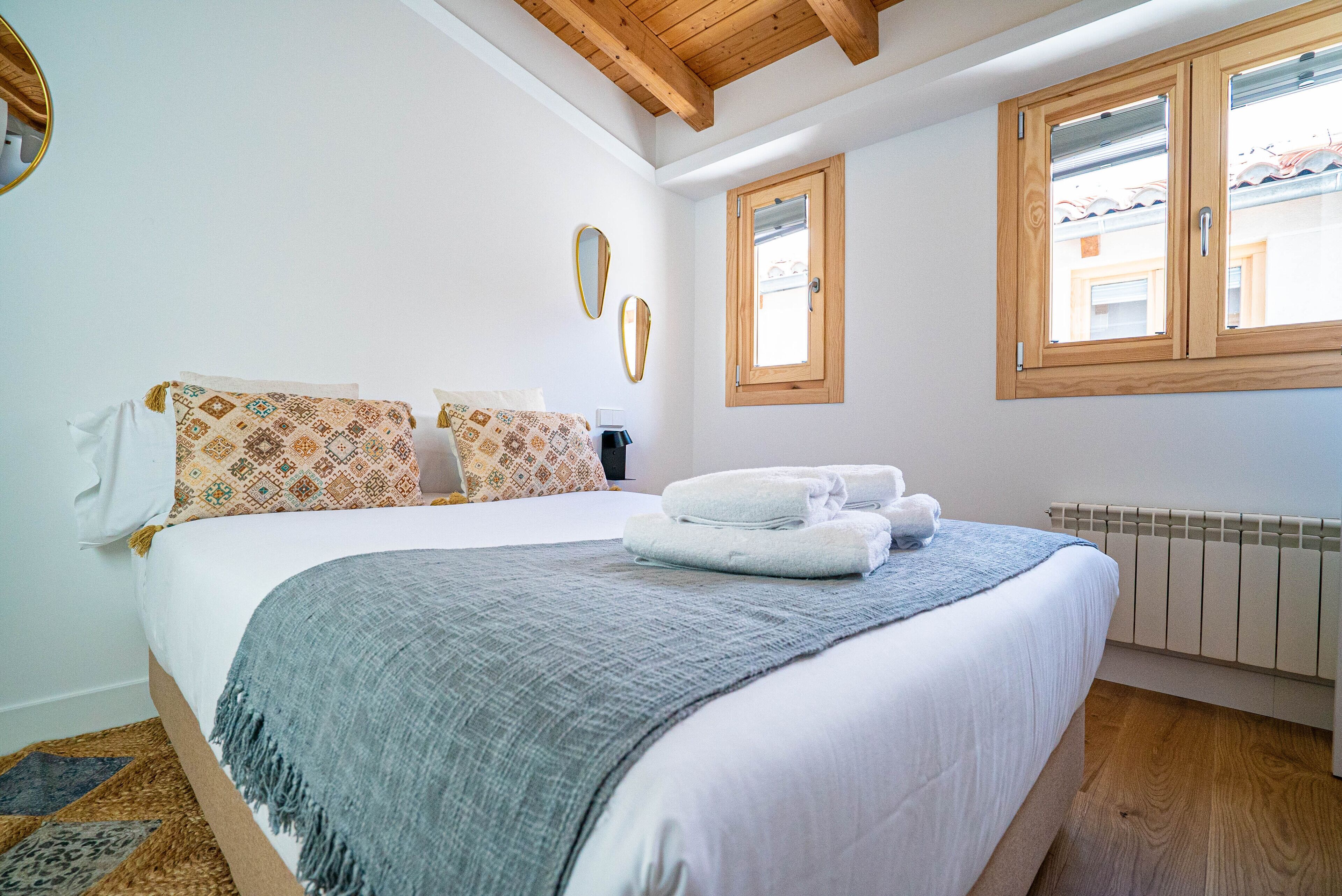 A bedroom with a large bed, a window with wooden frames, and a radiator.