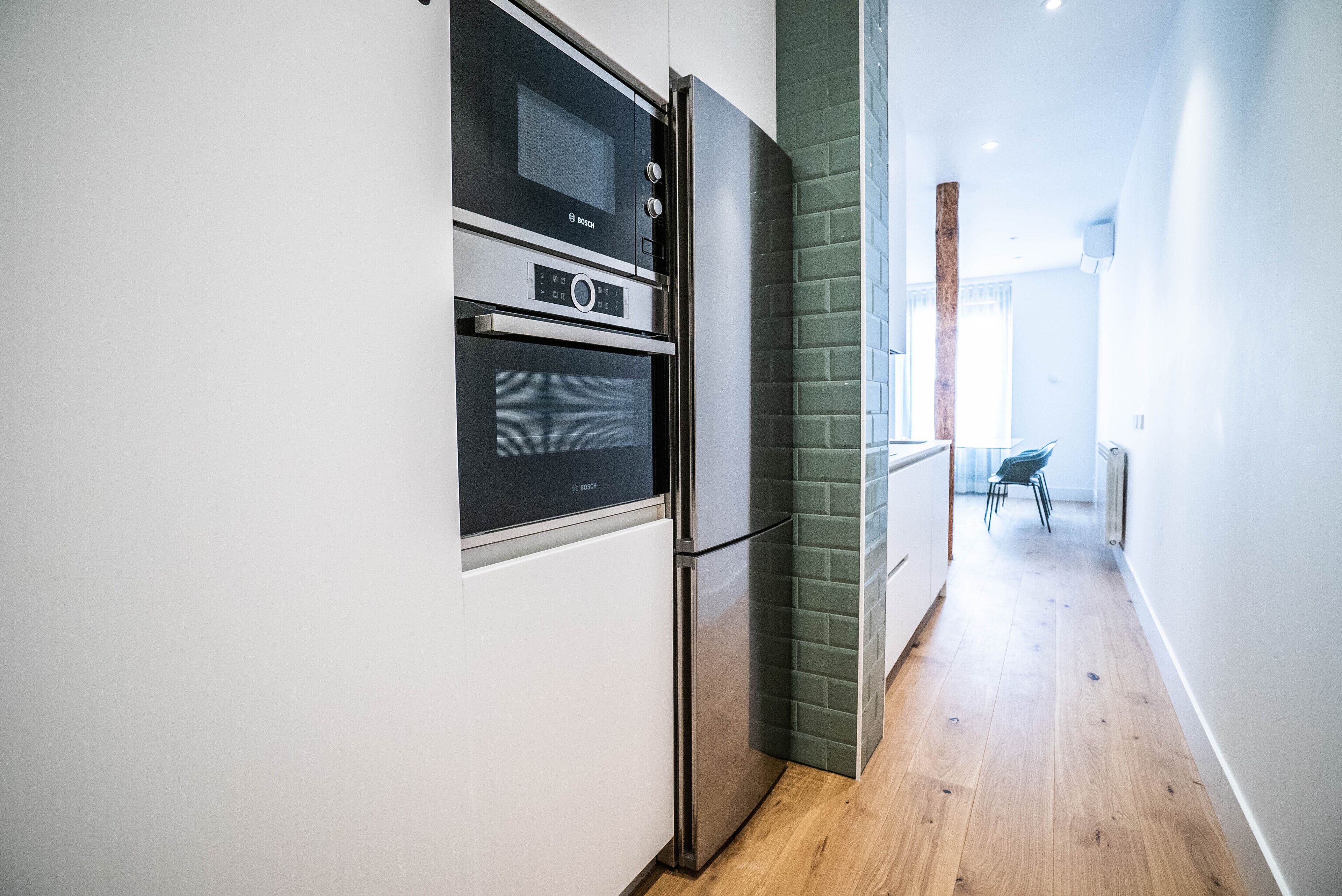 Una cocina moderna con electrodomésticos integrados, suelo de madera y vista al área de comedor.