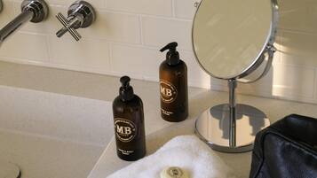 A bathroom with a bathtub, a round mirror, and two bottles of hand and body wash.