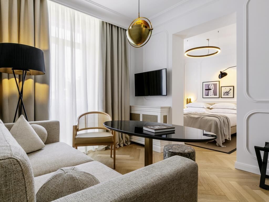 A modern living room with a sofa, a coffee table, a TV, and a bed with a headboard.