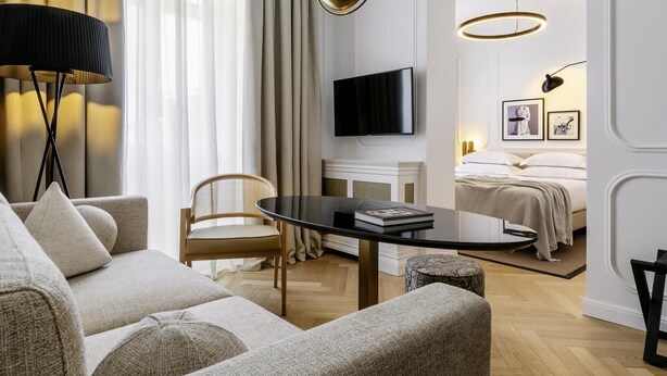 Un salon moderne comprenant un canapé, une table basse, un téléviseur et un lit avec une tête de lit.