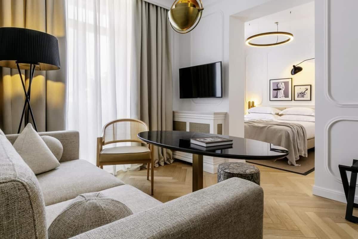 Una sala de estar moderna con un sofá, una mesa de centro, un televisor y una cama con cabecera.