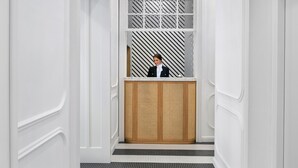 Un espace d’accueil comprenant un comptoir d’enregistrement, une fenêtre décorée et un sol à rayures.