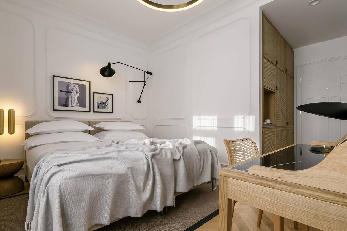 Un dormitorio moderno con una cama, mesitas de noche, un escritorio y una silla.