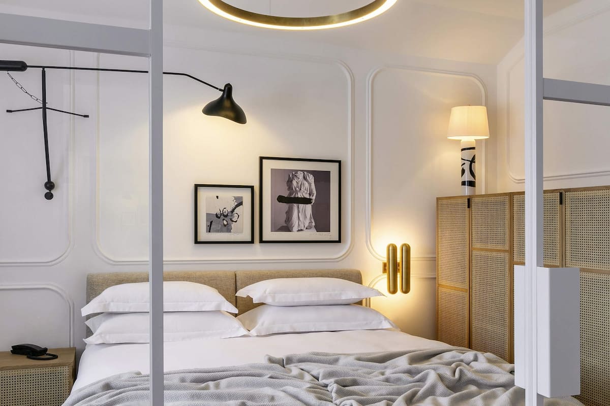 Un dormitorio moderno con cama, mesitas de noche, lámpara de pared y cuadro enmarcado.
