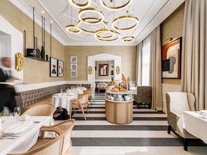 A hotel dining area with round chandeliers, a central buffet, and a view of the lobby. - Heritage Hotel Fermai (Split)