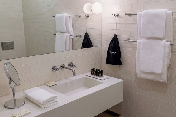 A bathroom with a large mirror, a sink, and multiple towels. - Heritage Hotel Fermai (Split)