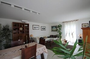 A living room with a dining table, sofa, and a bookshelf.