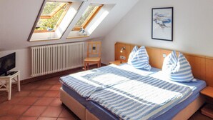 Ein Schlafzimmer mit Bett, Stuhl, Schreibtisch, Heizkörper und einem Bild an der Wand.