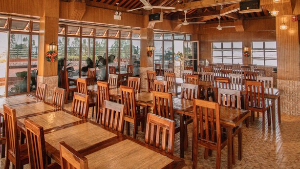 A spacious restaurant with wooden tables and chairs, large windows, and a high ceiling with exposed beams. - Hotel La Maria (Guiuan)