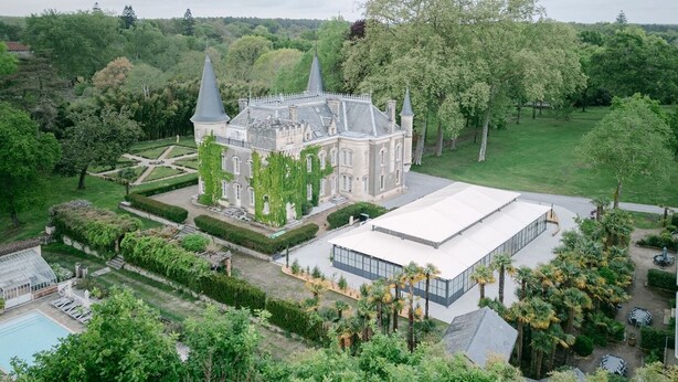 Een groot, historisch gebouw met een centrale binnenplaats, omringd door weelderige begroeiing en een zwembad.