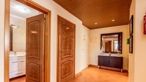 A hallway with wooden doors, a tiled floor, a dark wooden cabinet, and a mirror on the wall. - Apt. Casa Murrin, in a peaceful and secure complex with pool (Lagos)
