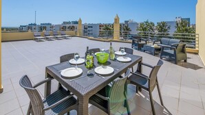 A rooftop terrace with a table set for dining, chairs, and a view of the cityscape. - Apt. Casa Murrin, in a peaceful and secure complex with pool (Lagos)