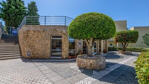 A stone building with a door and a staircase leading up. There is a circular stone planter with a tree in the center. - Apt. Casa Murrin, in a peaceful and secure complex with pool (Lagos)