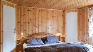 A wooden-paneled room with a bed, bedside tables, and a window with curtains.