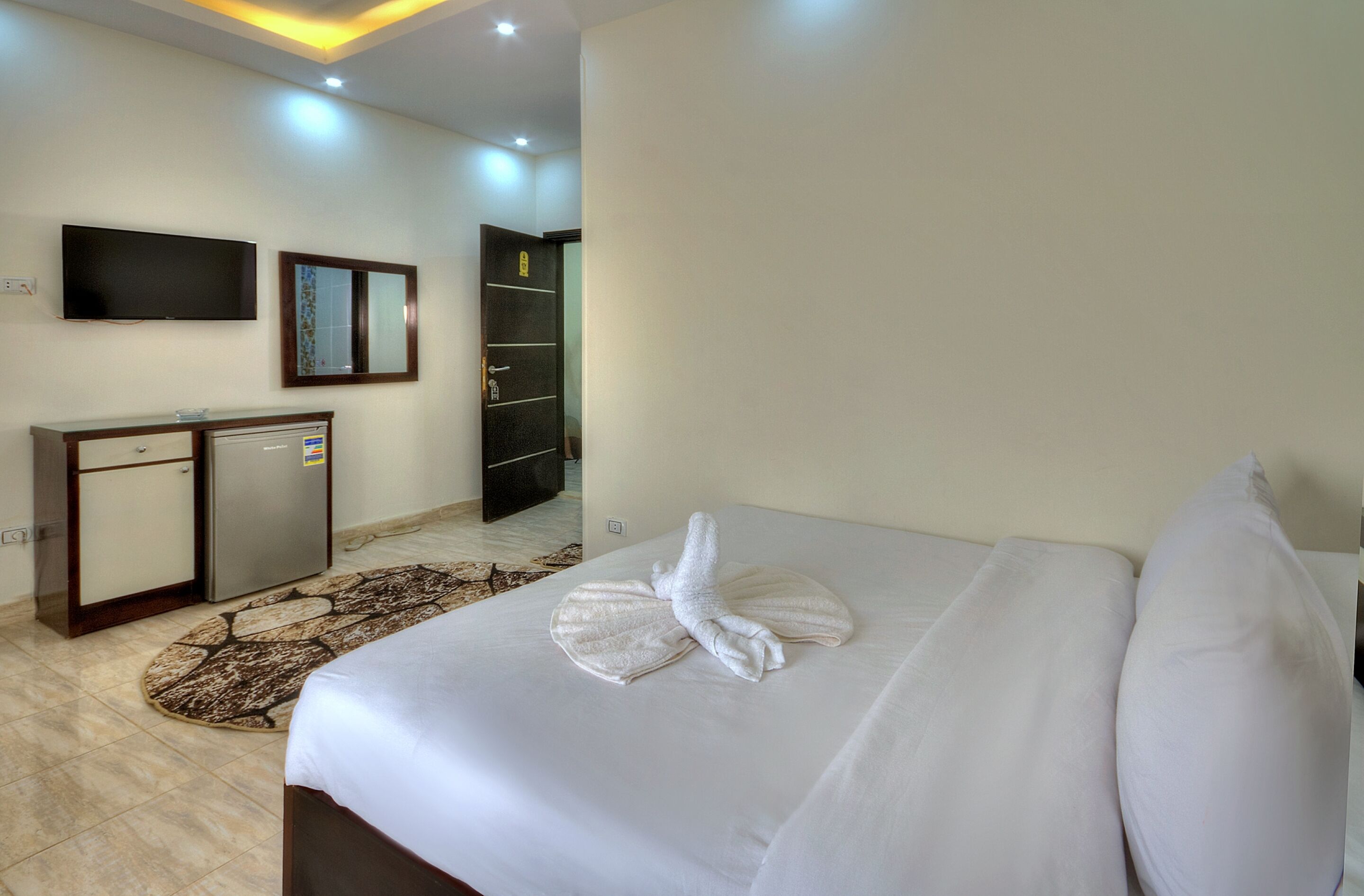 A hotel room with a bed, a desk, a television, and a wardrobe.