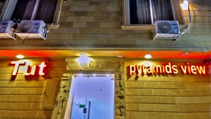 A building with multiple balconies, air conditioning units, and illuminated signage reading "Fut" and "pyramids view". - Tut Pyramids View Hotel (Giza)