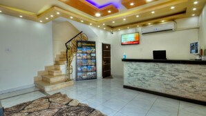 A hotel lobby with a reception desk, a staircase, and a wall-mounted TV. - Tut Pyramids View Hotel (Giza)