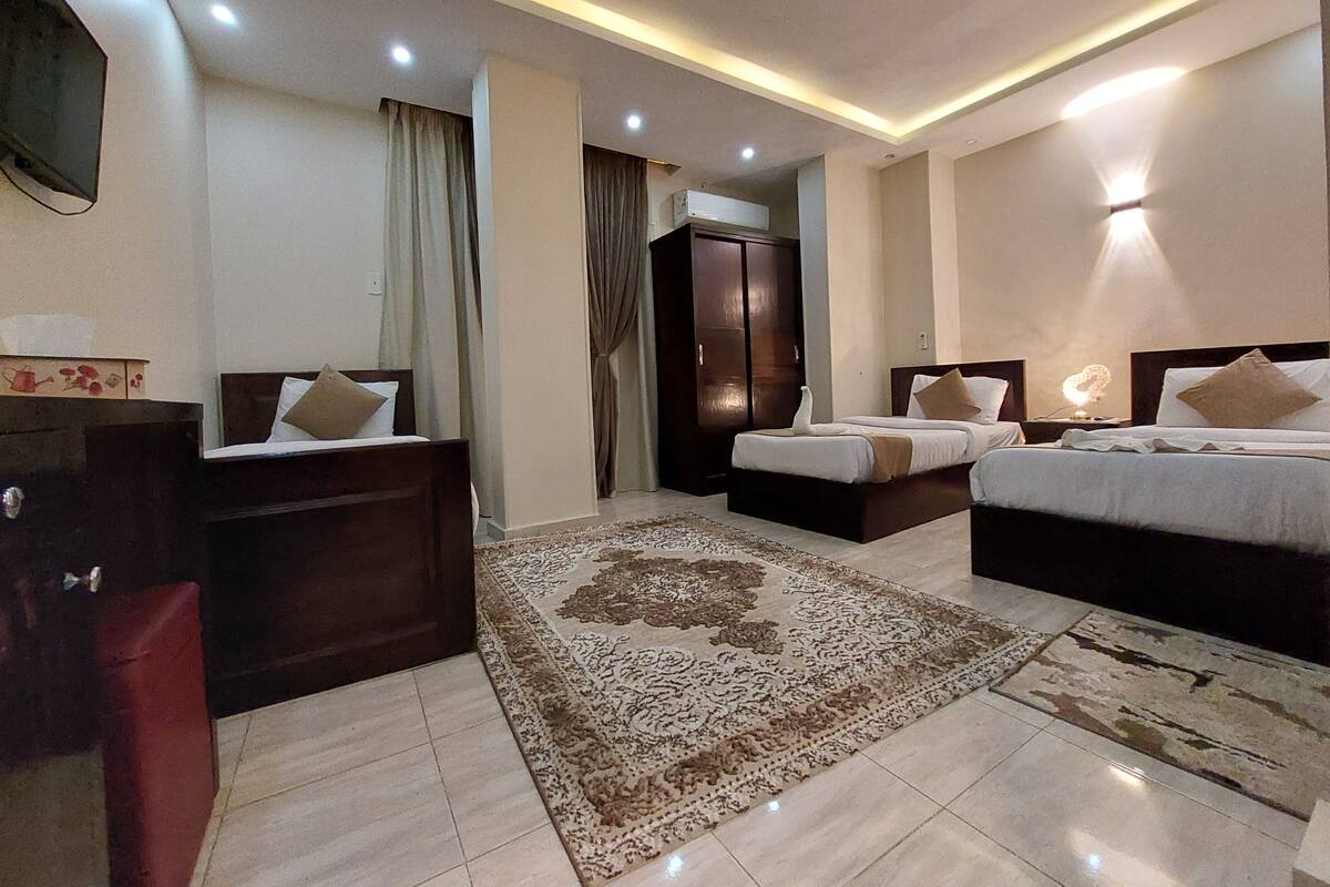 Habitació d'hotel amb dos llits, un armari, una taula de nit i una gran catifes.