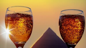 Two wine glasses with a sunset and a pyramid in the background. - Tut Pyramids View Hotel (Giza)