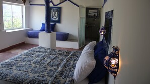 A bedroom with a bed, a window, a blue wall, and a door leading to another room. - Kasbah de Ouirgane (Ouirgane)