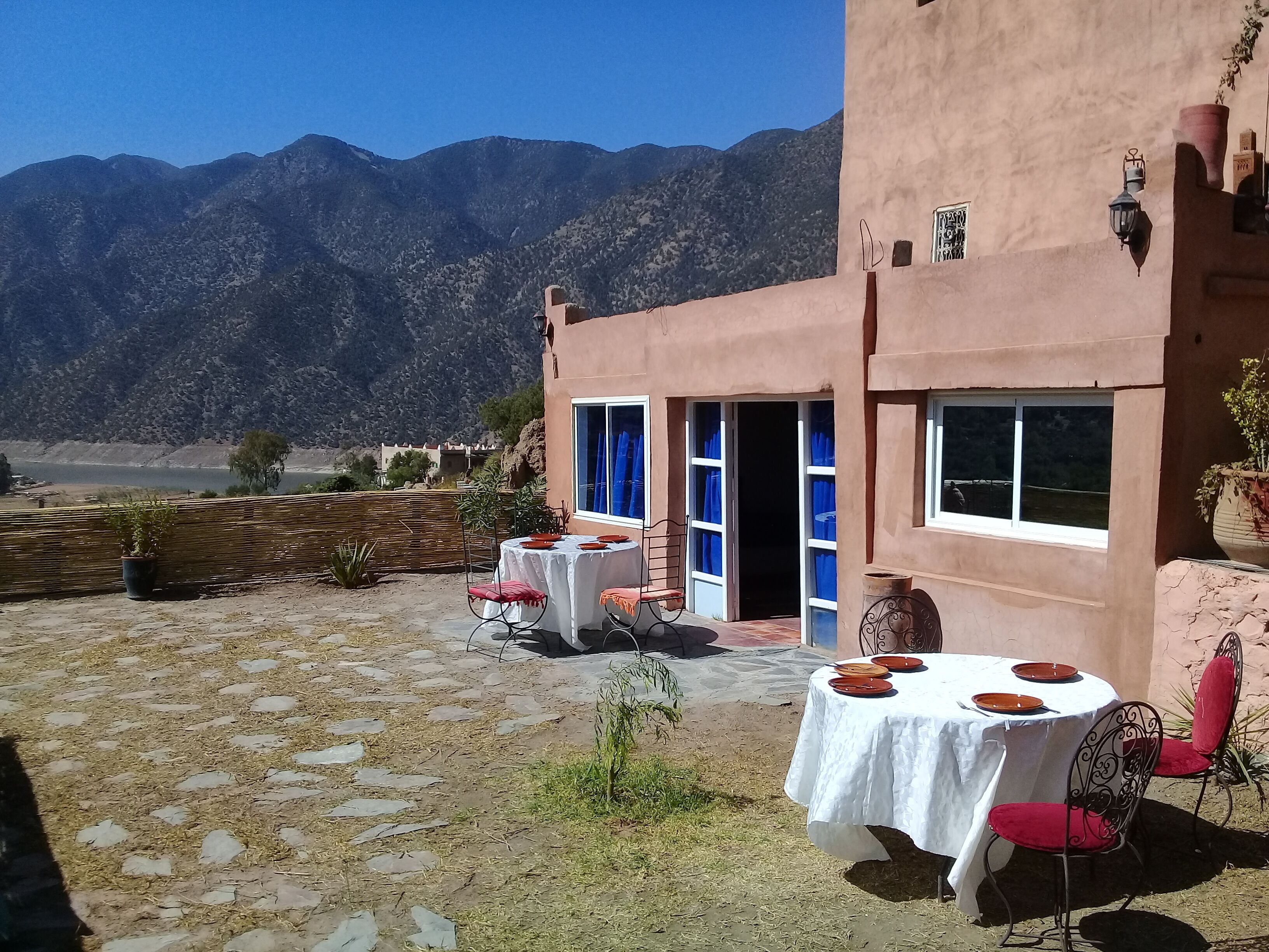 Un patio al aire libre con una mesa lista para comer, una silla y una maceta.