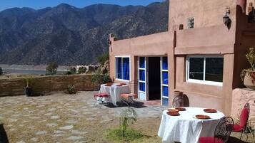 Un patio al aire libre con una mesa lista para comer, una silla y una maceta.