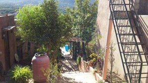 A narrow pathway leading to a building with a pergola, surrounded by greenery and a large water tank. - Kasbah de Ouirgane (Ouirgane)