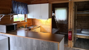 Una cocina compacta con armarios de madera, un microondas y un lavamanos.