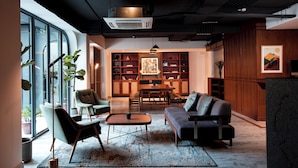 A modern living room with a sofa, chairs, a coffee table, and a bookshelf. - Nomad Hotel (Kathmandu)