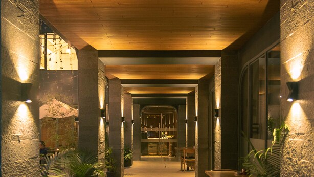 A corridor with wooden flooring, stone walls, and potted plants. - Nomad Hotel (Kathmandu)