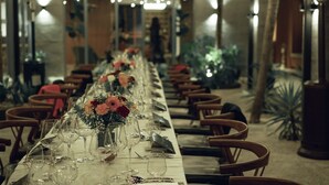 A long dining table set with glassware and floral centerpieces, surrounded by wooden chairs. - Nomad Hotel (Kathmandu)