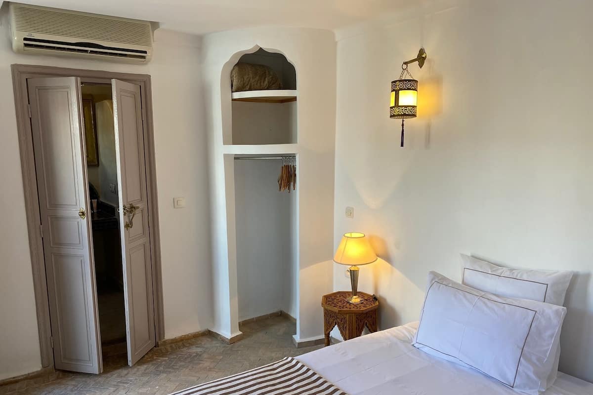Un dormitorio con cama, lámpara de noche, armario y lámpara colgante.