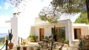 Uma casa moderna com varanda, móveis de exterior e plantas em vasos.