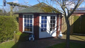 A small, single-story building with a red brick exterior and white trim. It features a large window with multiple panes and a white door. - Haus Eveline (Borkum)