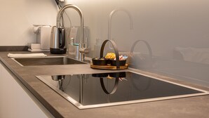 Una cocina moderna con electrodomésticos de acero inoxidable, una encimera negra y una sartén pequeña negra en el fregadero.