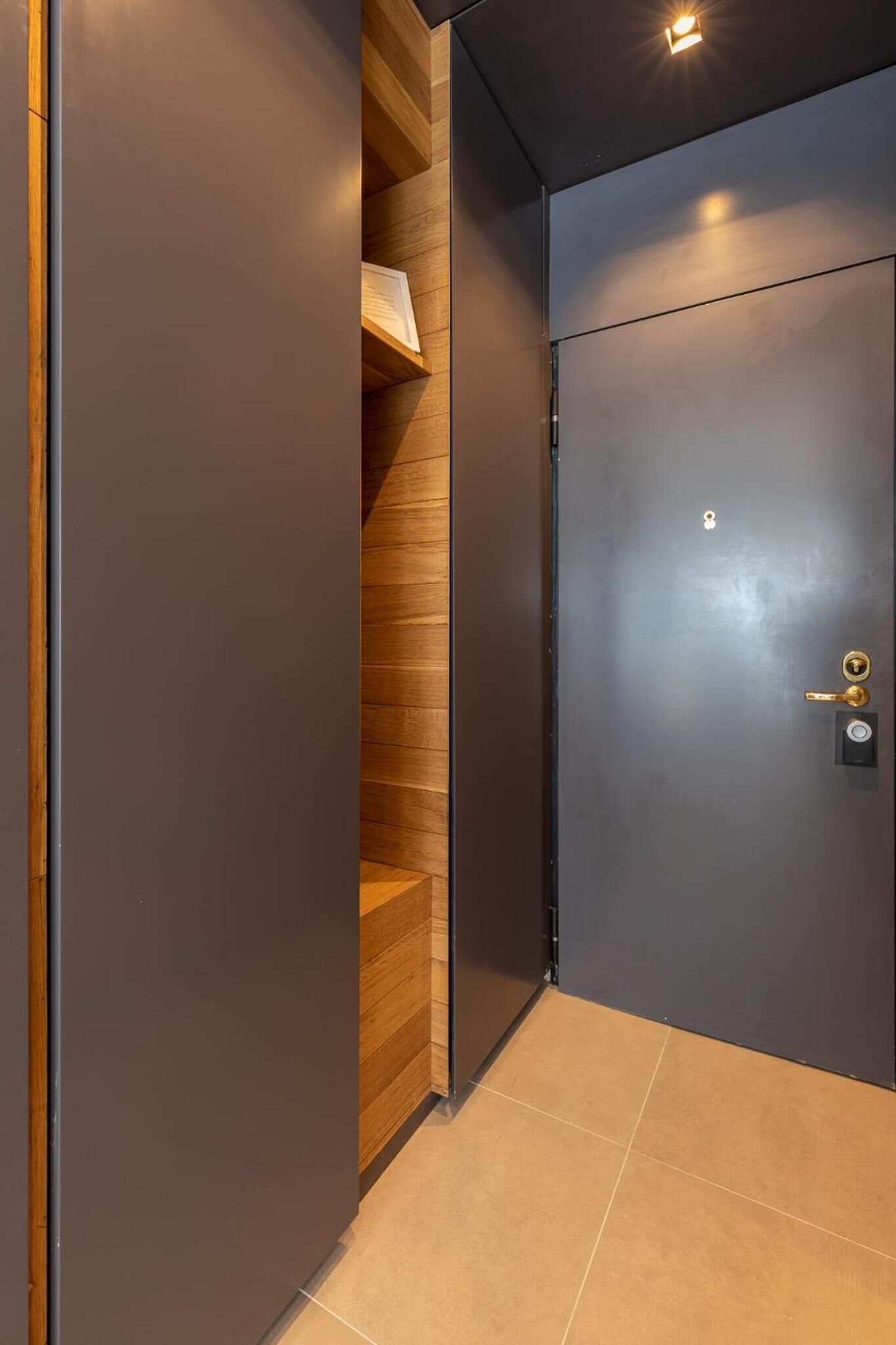 Un ascenseur moderne avec une porte sombre et un intérieur en bois.