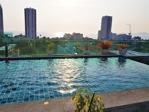 A rooftop infinity pool with a cityscape view, surrounded by potted plants. - Fantastic Roof top Pool! (Pattaya)