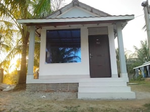 A small, single-story building with a dark brown door and a large window.