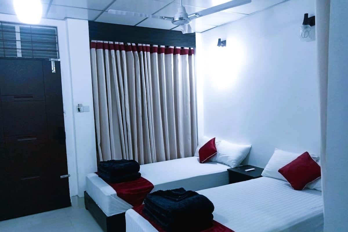 A hotel room with two beds, a ceiling fan, and a window with curtains.