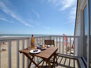 A wooden deck with a table set for breakfast overlooking a beach. -  Sandunes 2    (Camber)